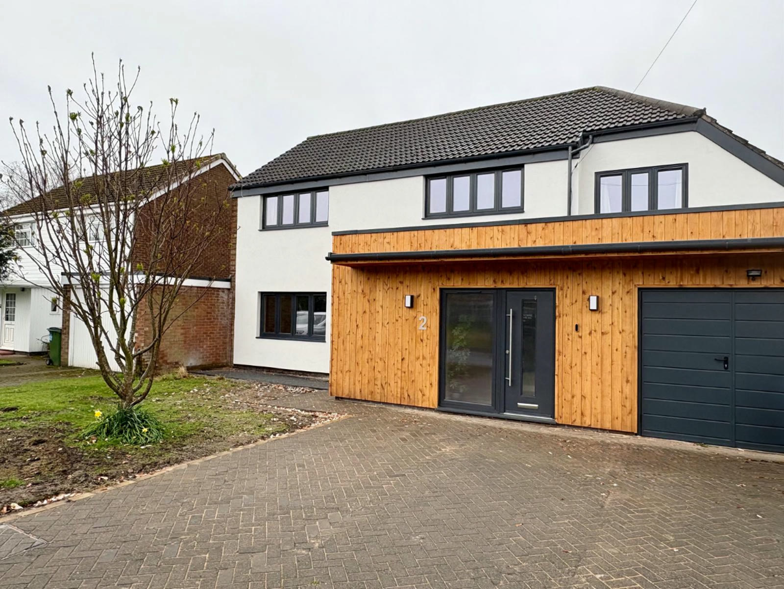 A full house finished in white silicone render alongside timber cladding