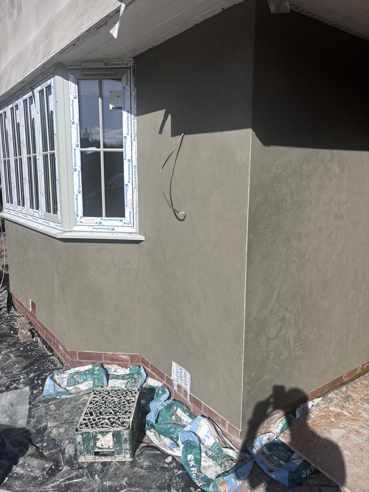 Reinforced basecoat worked flat across an elevation around a bay window