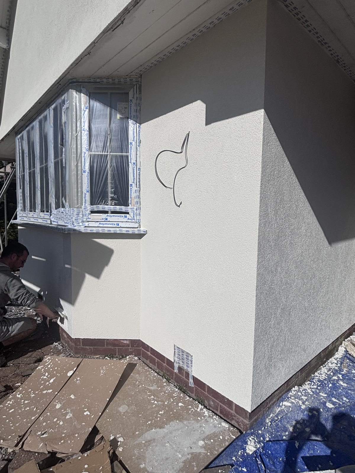 The finished elevation in white silicone render above a brick plinth